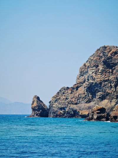 白天，蓝海边的褐色岩石山